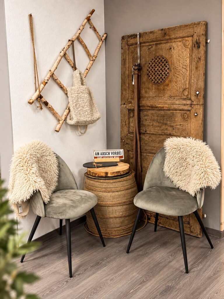 Zwei Sessel mit Fell, Holztür und Leiterdeko in der Sitzecke von HerzDame