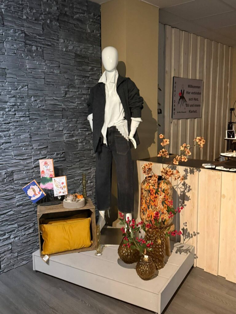 Schaufensterpuppe mit Herbstdeko vor der Steinwand bei HerzDame